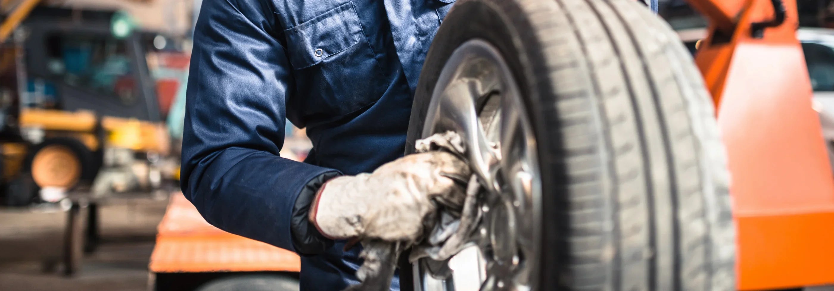 Worker wearing protective gloves carrying a tire on an industrial floor equipped with AAWipes non-slip, oil-absorbent industrial mats, demonstrating safety and contamination control